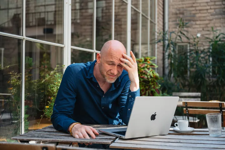 Marian Kamenistak with hand on forehead, looking at his laptop, contemplative.