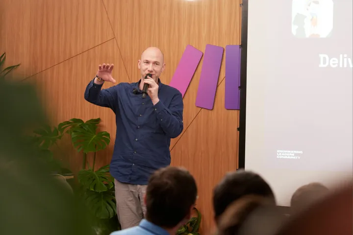 Marian Kamenistak speaking with a microphone at an Engineering Leaders Community event, hand raised mid-gesture.