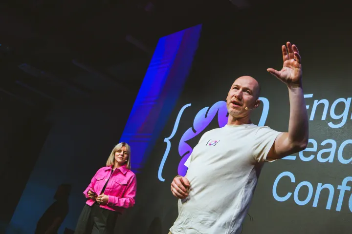 Marian Kamenistak on the main stage of the Engineering Leaders Conference, arm raised, co-host in the background.